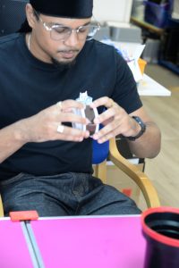 A young man learning to wind film onto a developing spool