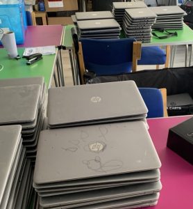 Green and pink tables with laptops stacked up on them