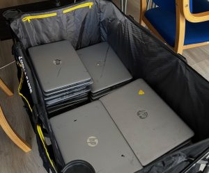 A large festival trolley containing piles of silver laptops