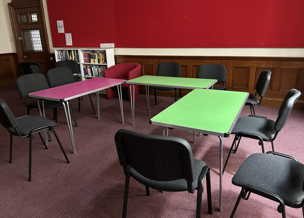 A room with pink and green tables with chairs