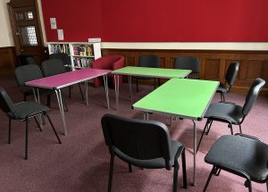 A room with pink and green tables with chairs