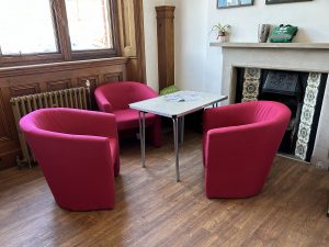A staff room with three comfy chairs and a table.