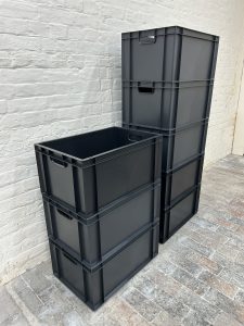 Two piles of study black plastic boxes next to a wall